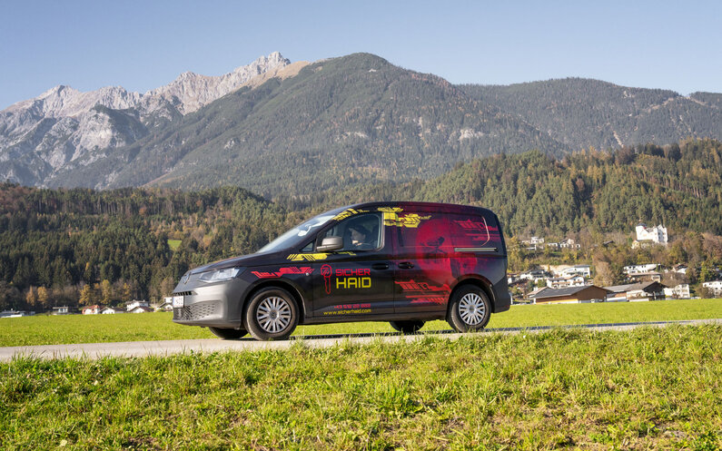 Ein Bild, das einen Firmenwagen in einer Gebirgsszenerie darstellt.