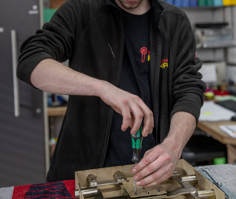 Das Bild zeigt einen Mitarbeiter bei einer Reparatur eines Tresors.