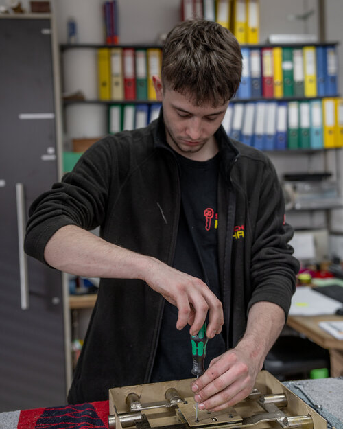 Das Bild zeigt einen Mitarbeiter bei einer Reparatur eines Tresors.