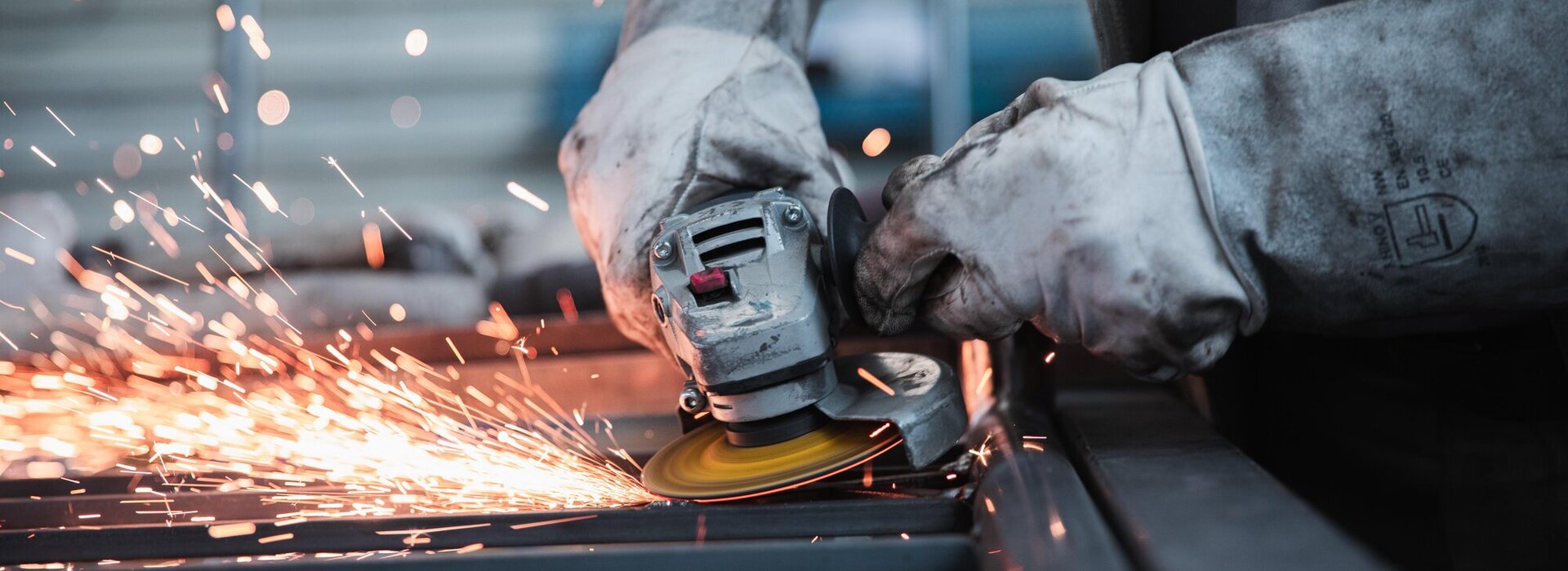 Das Bild zeigt einen Arbeiter beim Verwenden eines Winkelschleifers. 