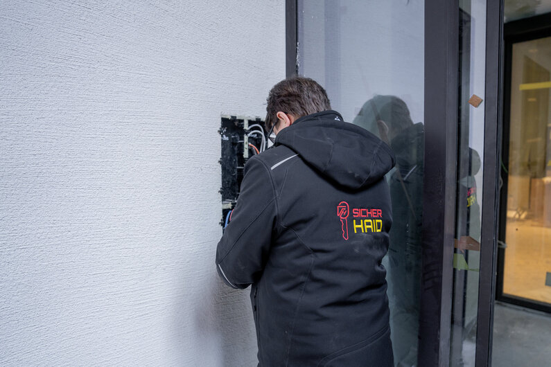 Das Bild zeigt einen MA bei der Montage einer Gegensprechanlage.